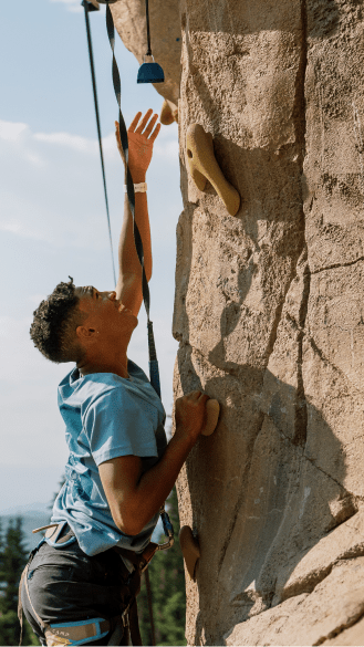 young man reaches for a rock climbing hold at the snowmass climbing wall
