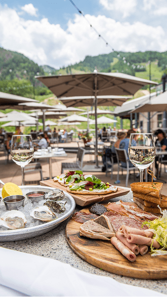 View of Ajax Tavern dishes, under sun umbrellas, oysters, steak and fresh glasses of wine