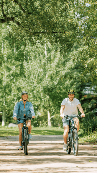 two people on bikes under large green trees in Aspen