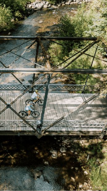 People on e-bikes over bridge in aspen