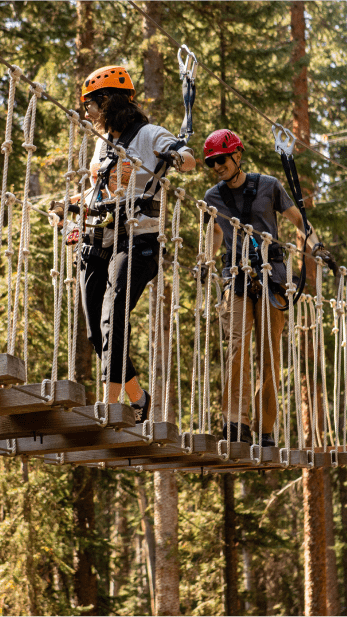 couple walks along sky bridge in Snowmass ropes course