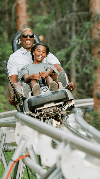 Two people ride down the alpine coaster at snowmass