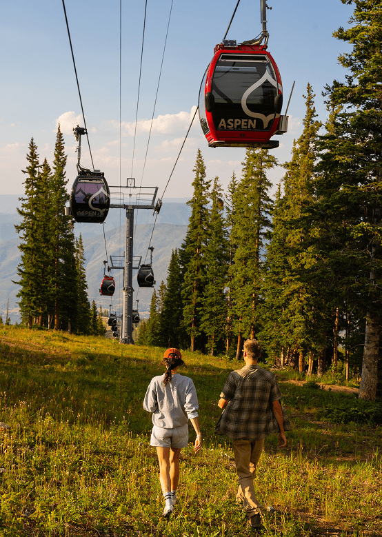 Couple walk under the gondola on aspen mountain in the summer