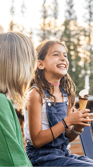 Little girl laughs as she holds an icecream cone between her hands at Elk Camp Snowmass