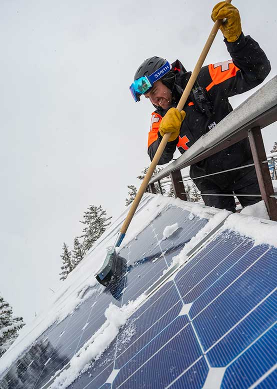 A ski patrol employee brushes snow off a solar panel
