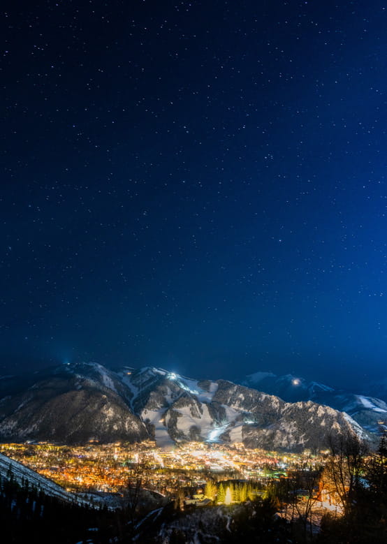 An aerial view of downtown Aspen and the mountains lit up at night.