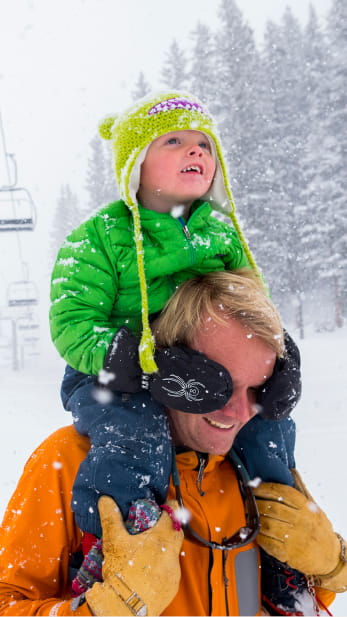 Man with small child on his shoulders playing in the snow