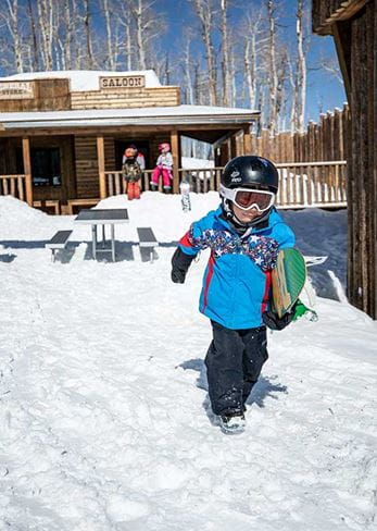 A young boy with his snowboard at Fort Frog