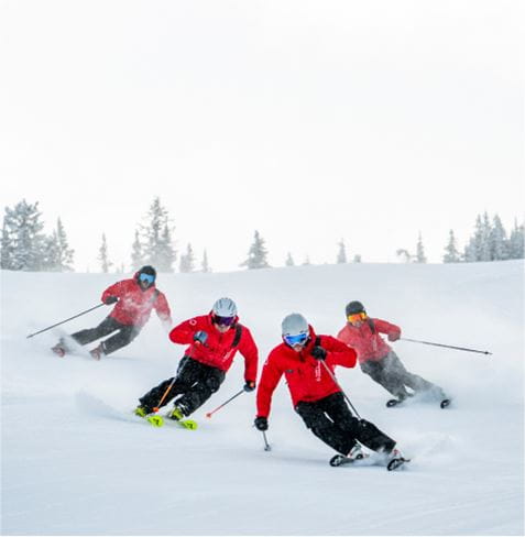 4 ski pros skiing in unison on a ski slope