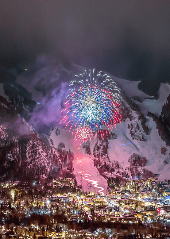 Blue, pink and purple fireworks over the town of Aspen, lit up on a snowy winter night