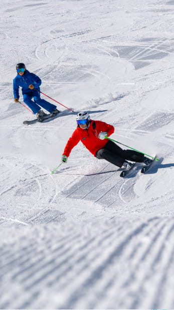 Ski pro and a guest carving on a groomed ski slope