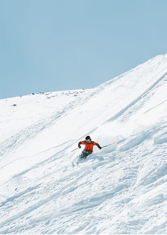 skier carves through knee deep powder at Aspen Snowmass