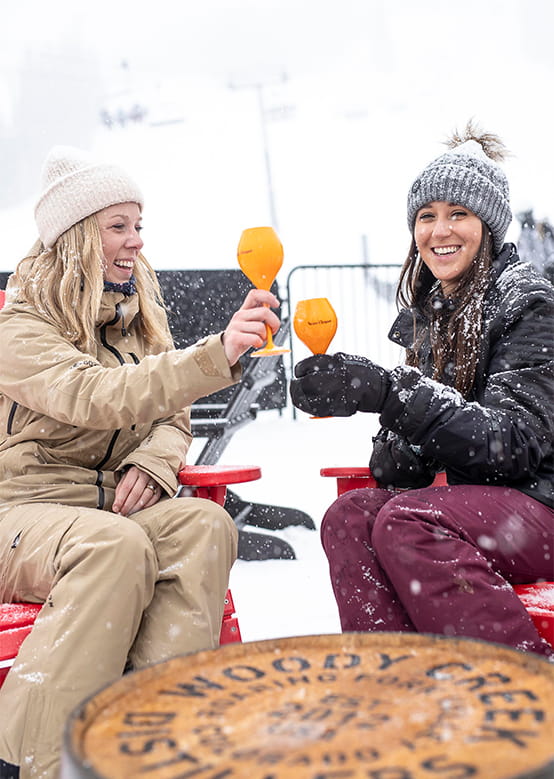 Two women cheers their glasses during après at Aspen Snowmass, the Cabin