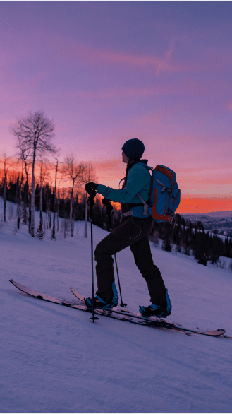 person uphill at dusk, pink, red and purple skies illuminate them from behind