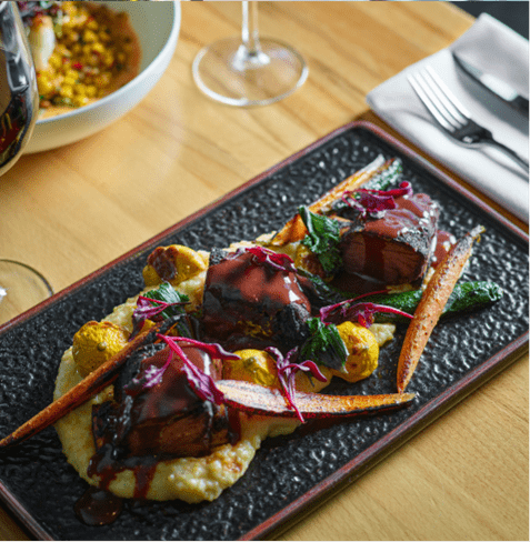 Long plate with seasonal roasted veggies, atop buttery grits