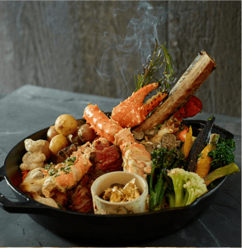 cast iron skillet of surf and turf at Cloud nine, lobster, crab claw, and bone barrow are a few of the foods