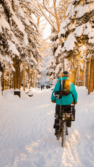 Man bikes down main street on a snowy day in aspen snowmass