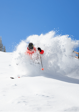 skier in powder at aspen mountain under blue skies
