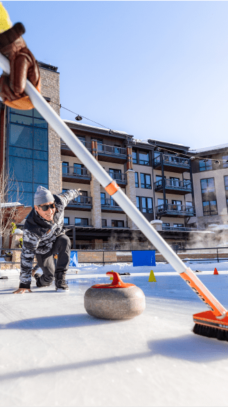 Curling on the ice rink at snowmass skating rink, a man is in a lung on the ice