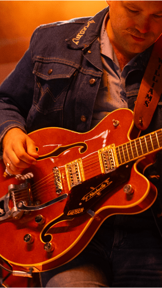 Man plays his red electric guitar at live music at Snowmass