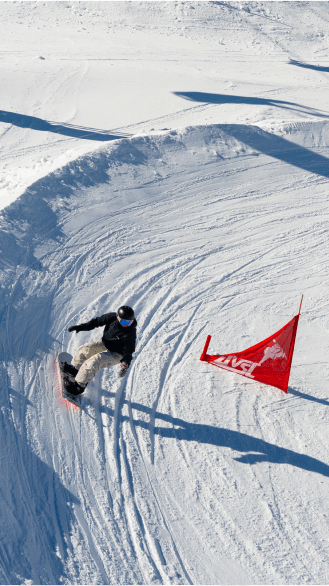 Snowboarder takes a sharp turn around a red racing flag during a racing event at Snowmass