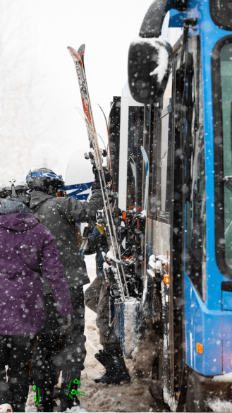 Man loads skis on the side of the RFTA bus at Aspen Snowmass