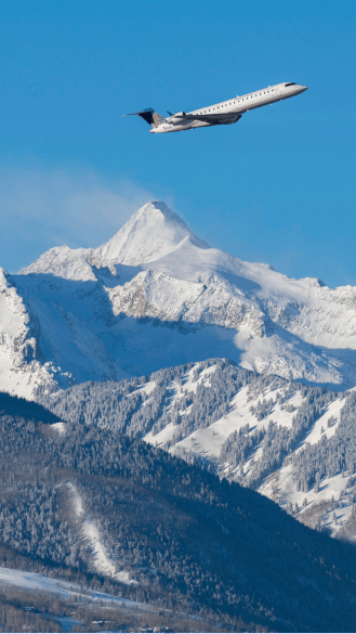Plane departs over a snow peak from aspen airport, on a blue bird day