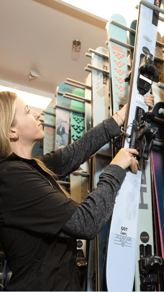 woman at Four Mountain Sports loads a pair of skis into the rental rack at Aspen Snowmass
