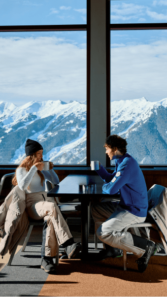 couple sits at aspen mountain's sundeck in their ski gear