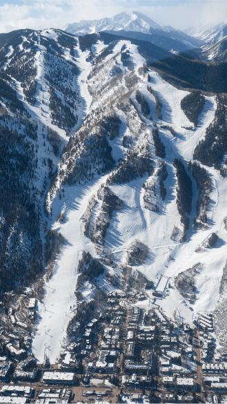Aerial view of Aspen Mountain, snowy ski runs leading down to the down of aspen