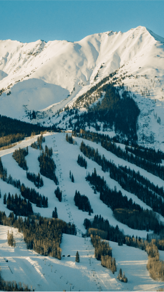Aerial view of snowmass ski resort, under even higher, untouched white peaks