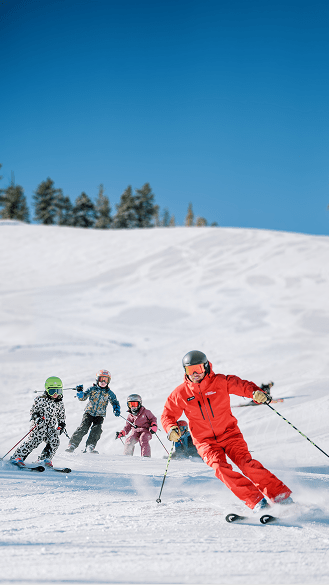 Kids follow ski pro at aspen lesson
