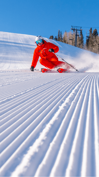 Single ski instructor carves through groomed snow at aspen mountain