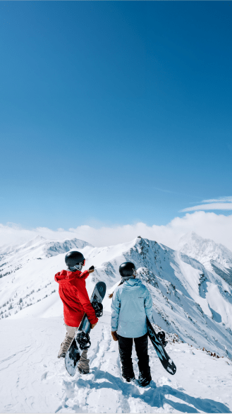 Two people, one instructor and one student, stand atop aspen highlands bowl on a blue bird day