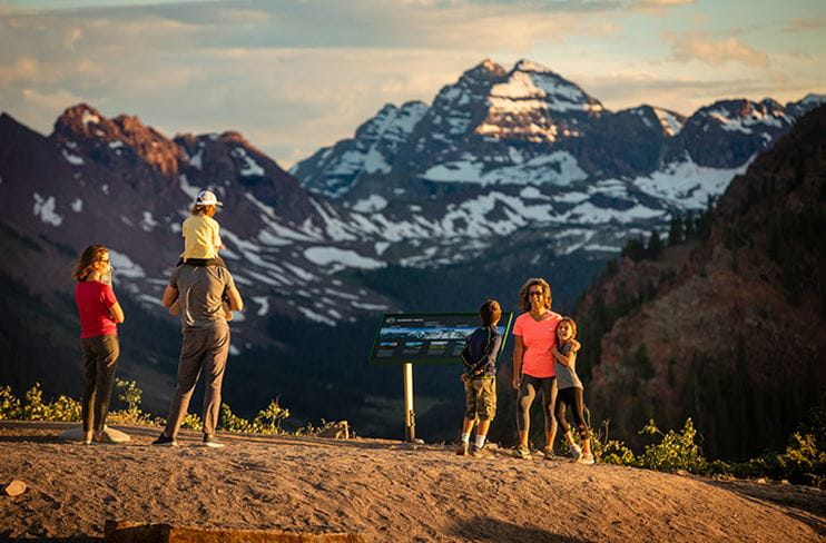 Hikers enjoy a view of the distant Maroon Bells