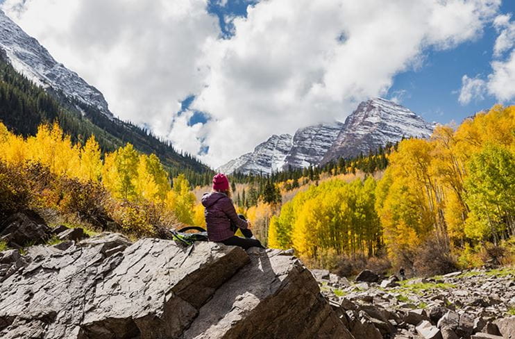 A hiker enjoys the fall color underneath Maroon Bells.