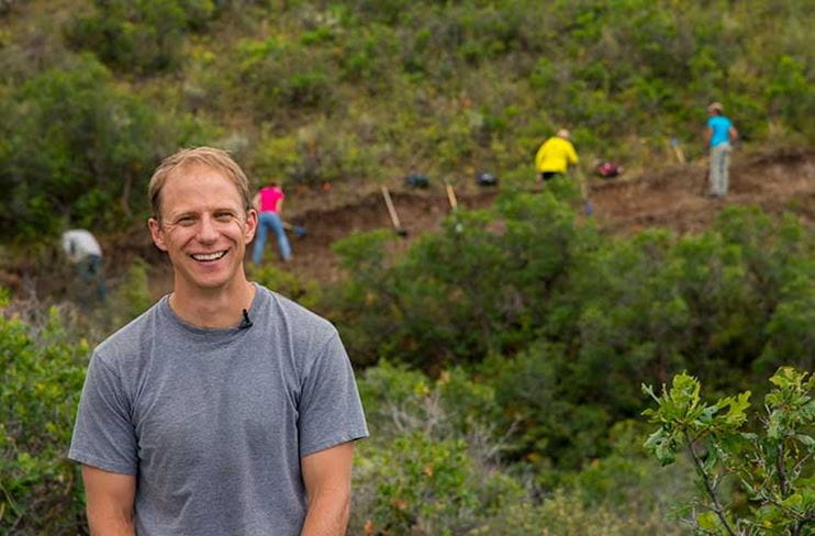 An Aspen Skiing Company employee smiles while volunteering for a trail crew
