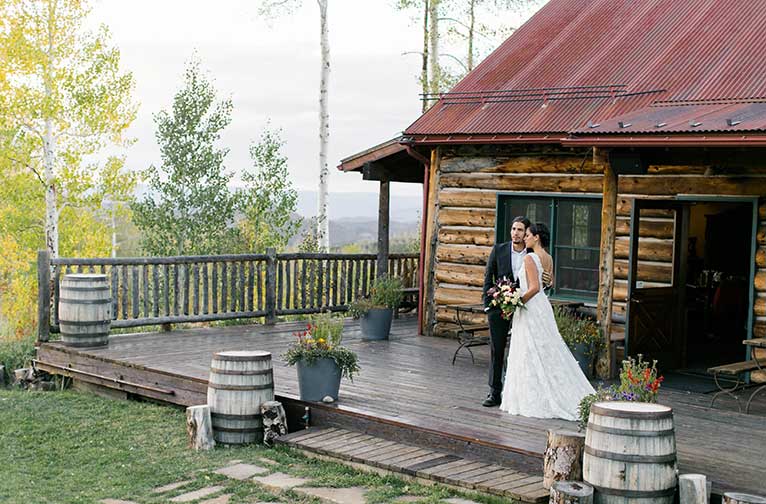 A bride and groom take wedding photos outside the western-style Lynn Britt Cabin.