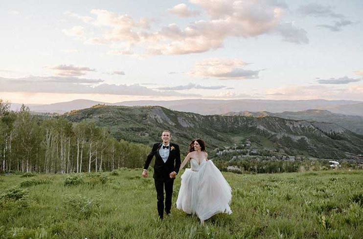 Couple runs through a meadow at Snowmass after their wedding