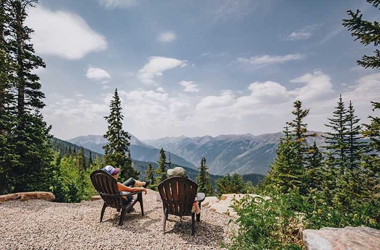 Two guests sit and enjoy the summer views atop Aspen Mountain.