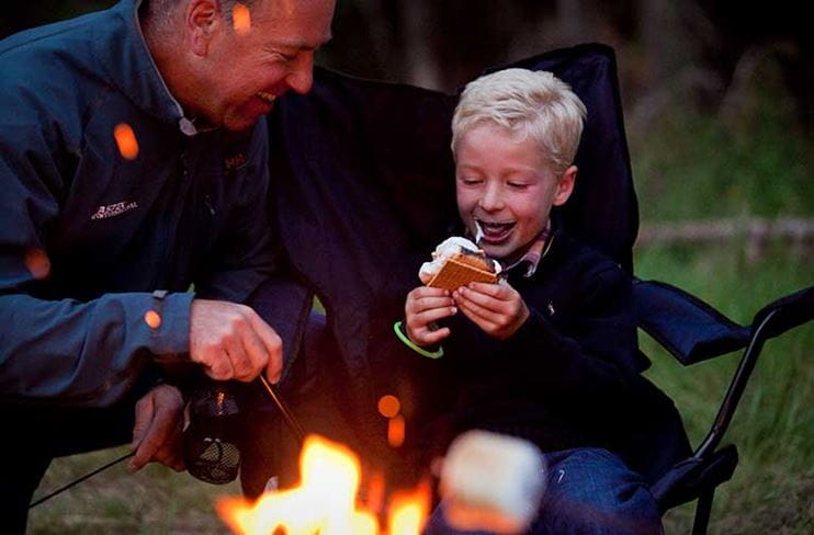 A father and son enjoy s'mores by the campfire