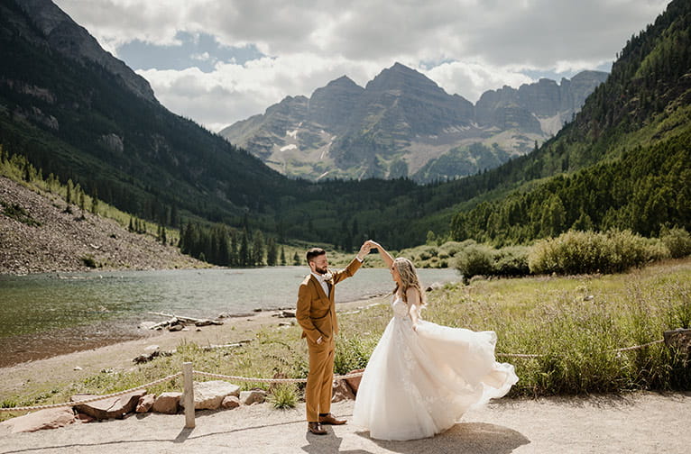 A wedding couple dances at Maroon Lake with Maroon Bells in the distance, near Aspen, Colorado