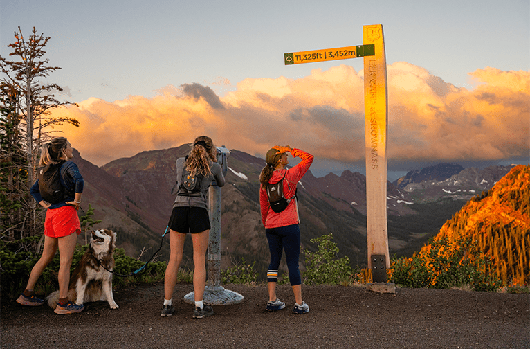 Three woman take in the view at the top of their hike at Aspen Snowmass
