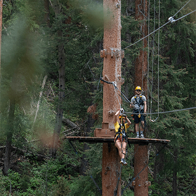 Zipliner takes off from platform in the trees at Snowmass Lost Forest