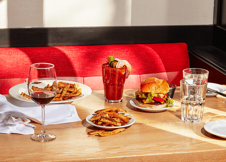 Limelight aspen lobby, dining experience, plates of burger, fries and drinks on a wood table with red booths