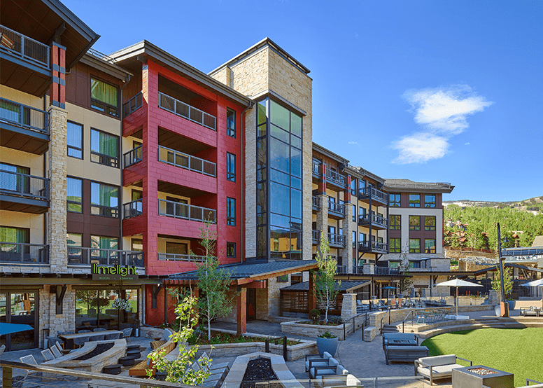 Limelight Snowmass during a summer day, blue skies above the hotel and green lawn