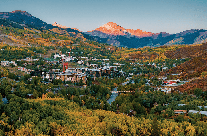 Aerial view of the town of snowmass and the ski runs above, as the valley turns gold with fall colors