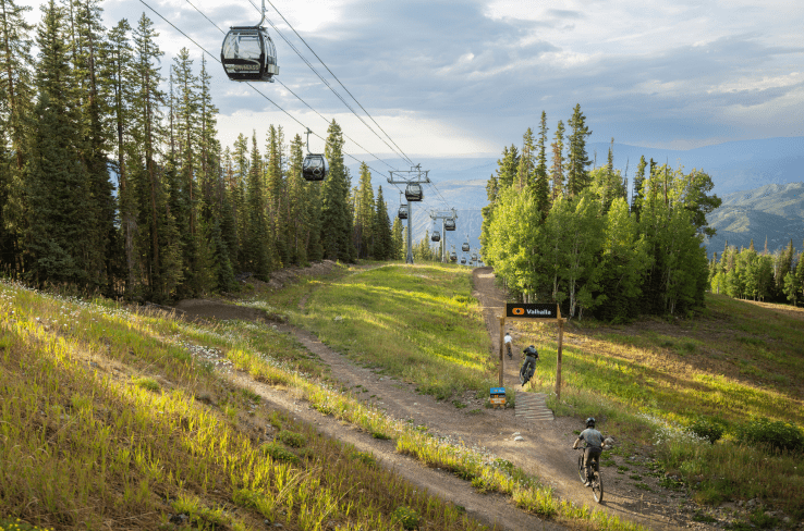 People riding down trail under gondola at snowmass