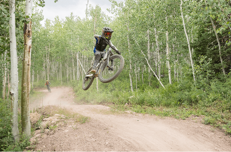 Two young downhill bikers ride through the snowmass bike park