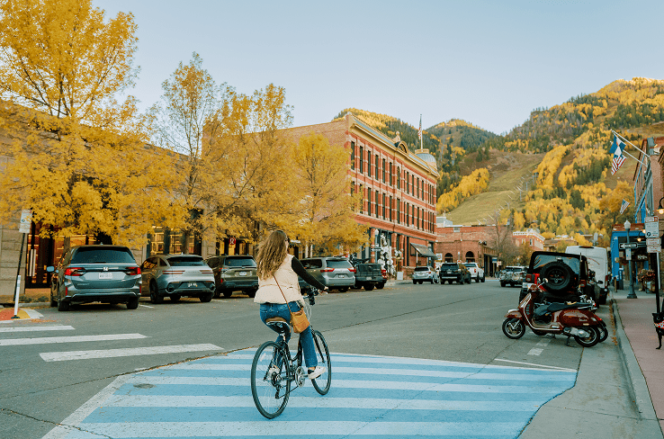 Woman rides on cruiser bike through the streets of aspen during fall